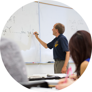 Professor writes math equation on white board