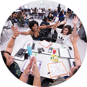 Group of students high five at desk