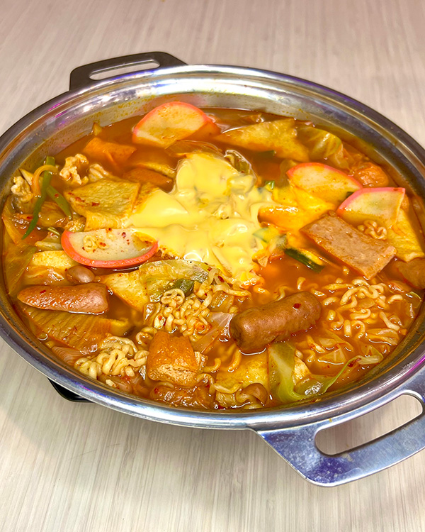 A bowl of Army Stew with sausage eggs, tomatoe, and noodles from Pocha Eats