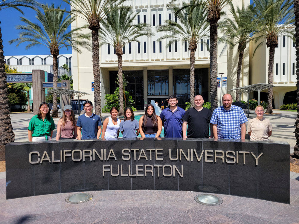 Graduate student in Petit research lab posing in fronr of CSUF landmark. 