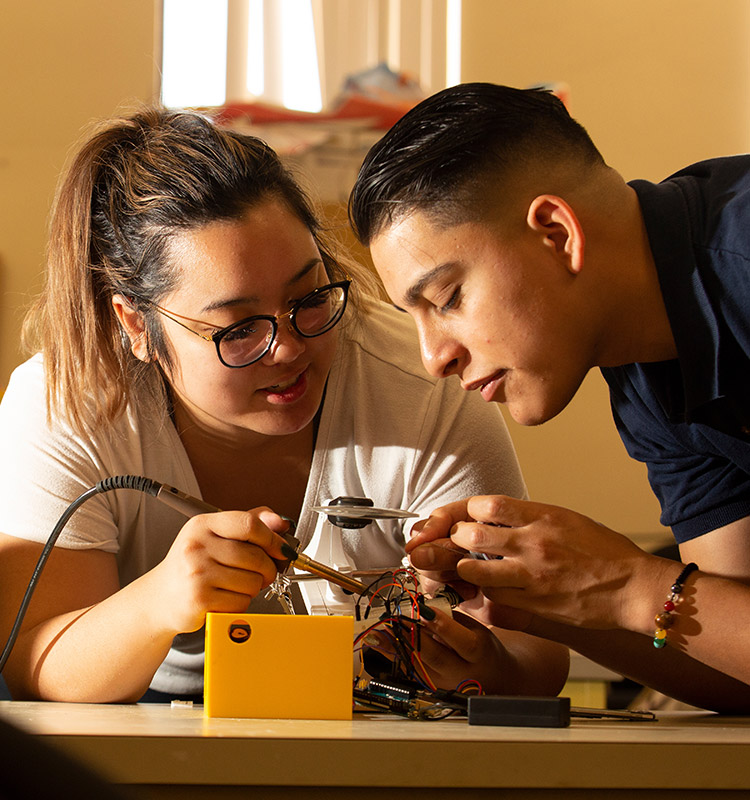 2 electrical engineering students working on circuit board