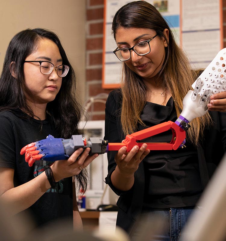 2 students examining 3D printed prosthetic arm
