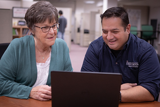 Two CSUF staff and faculty members checking out new technology on a laptop